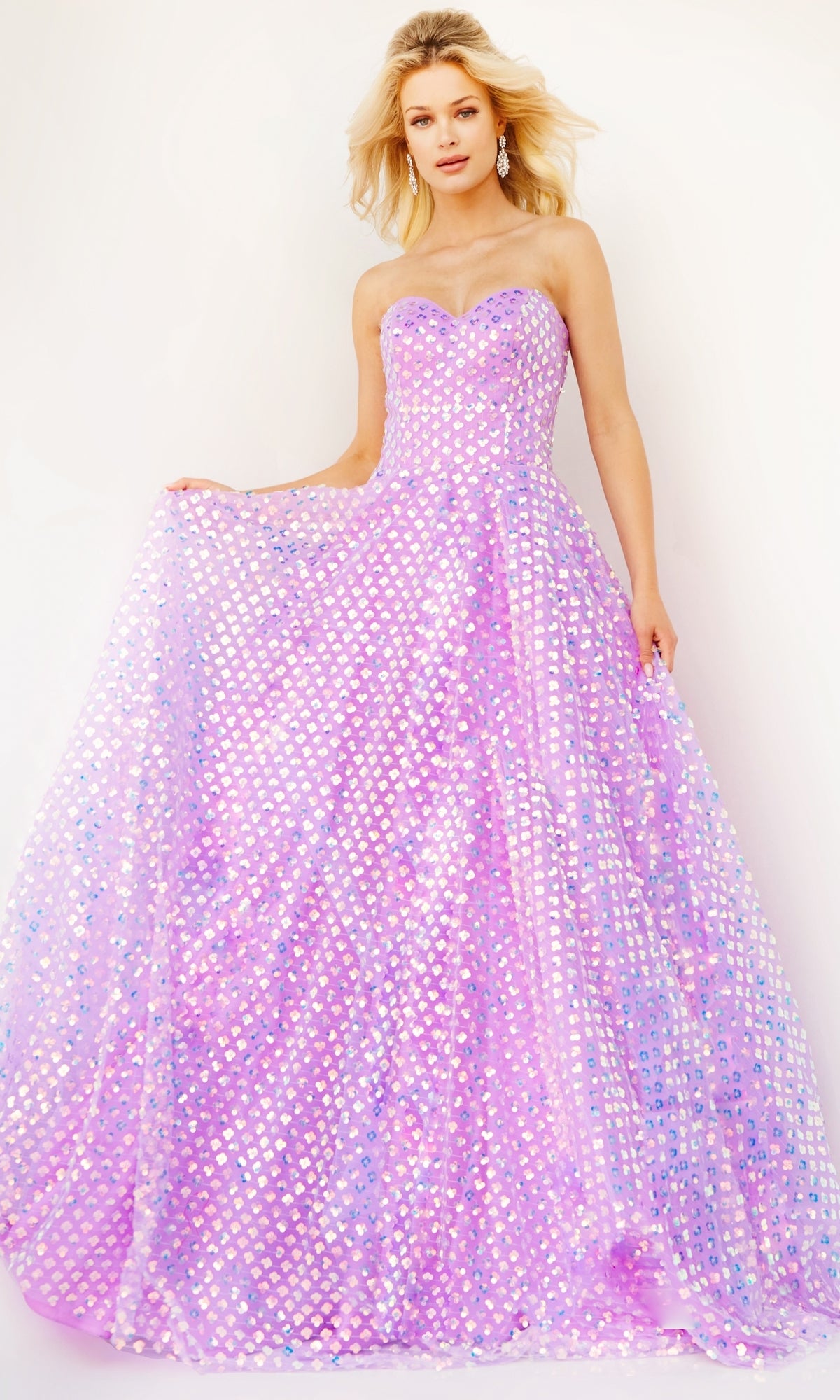 A woman stands against a plain light background wearing the Jovani Strapless Sweetheart Long Prom Dress 08605—an iridescent purple and pink gown with geometric sequin pattern.
